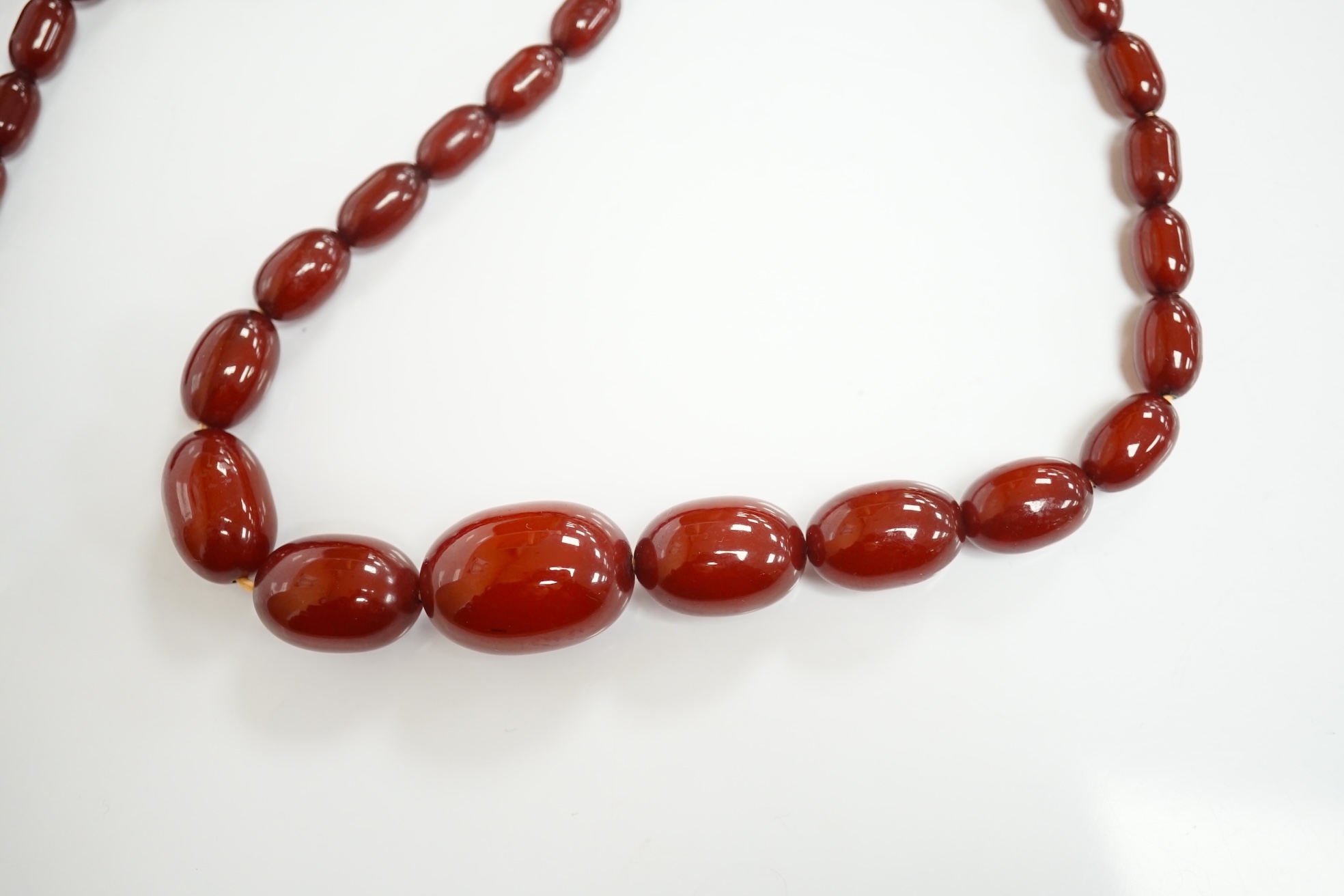 A single strand graduated simulated cherry amber oval bead necklace, 70cm, gross weight 51 grams. Condition - fair to good